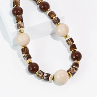 Necklace featuring mocha and cream beads with gold accents, arranged in a stylish pattern.