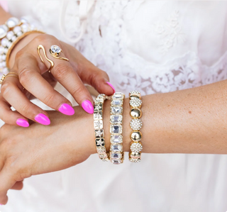 A set of gold-tone bracelets with crystal embellishments, worn on a wrist.