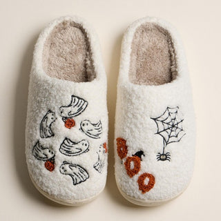 Cream fuzzy slippers with ghost and spider web embroidery designs.