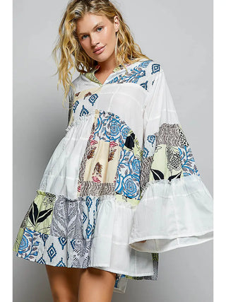 Model wearing a V-neck dress with ruffle sleeves in an ivory multi-color printed pattern.