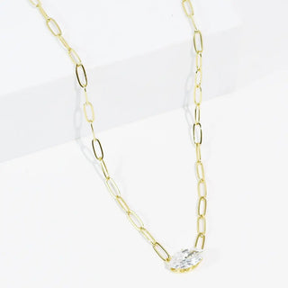Gold chain necklace with a crystal drop pendant displayed on a white surface.