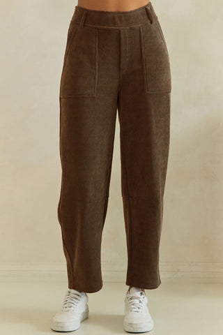 Brown corduroy barrel pants with a relaxed fit, shown from the front with sneakers.