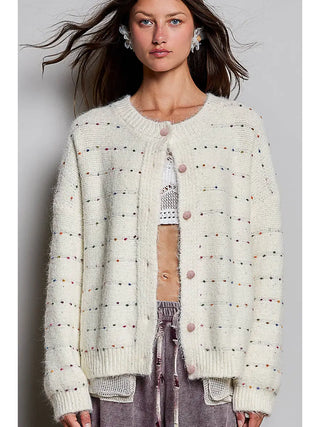 A cream knit cardigan with multicolor dots, crew neckline, and button front closure.