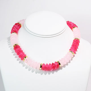 Pink and gold beaded necklace displayed on a white bust.