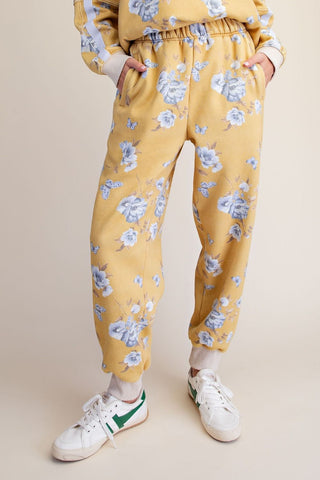 Mustard jogger pants with floral print, elastic waistband, and ribbed cuffs.