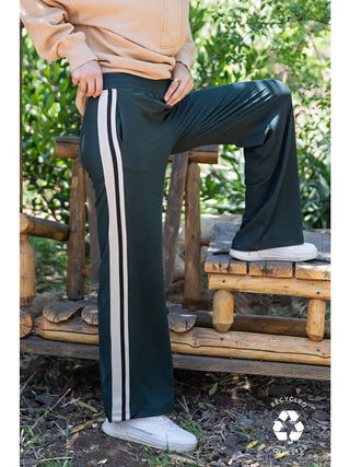 Person wearing Regency Green straight pants with white side stripes, standing outdoors.