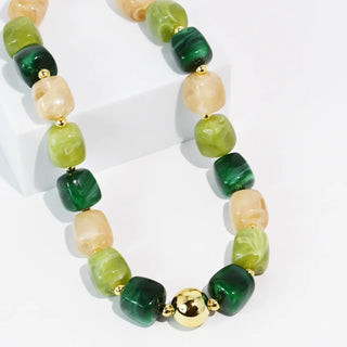 Chunky green and beige resin bead necklace with gold-toned accents.