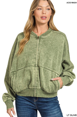 A woman wearing a light olive acid washed fleece jacket with a front zip closure.