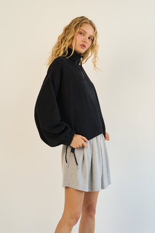 Black terry half-zip pullover with adjustable drawstring hem on a model.