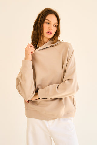 A woman wearing a light taupe hoodie with a soft fabric and relaxed fit.