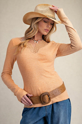 A woman wearing a persimmon rib knit top with lace inset, paired with a hat and jeans.