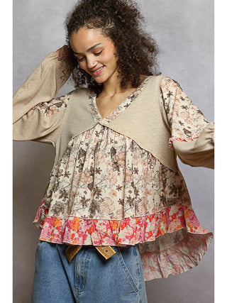 A woman wearing a patchwork ruffle top in toasted almond with floral prints and ribbed knit fabric.
