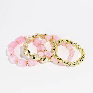 A set of three pink and gold-toned beaded bracelets.
