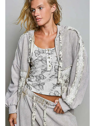 A woman wearing a sand-colored double gauze hooded thermal with a floral inner top.