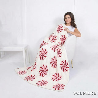 White and red blanket with a peppermint candy pattern, draped over a chair.