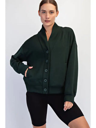 A woman wearing a Regency Green cardigan with a button front and long sleeves.