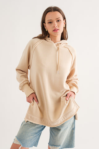 A woman wearing a cream-colored soft fleece hoodie with a relaxed fit.