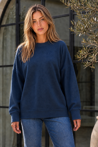 A woman wearing a relaxed-fit sweatshirt in midnight teal.