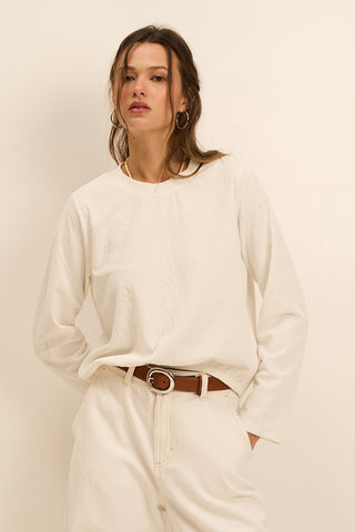 Model wearing a white long-sleeve top with a textured finish.