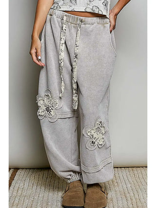 High-rise jogger pants in sand with floral print patches and a relaxed fit.