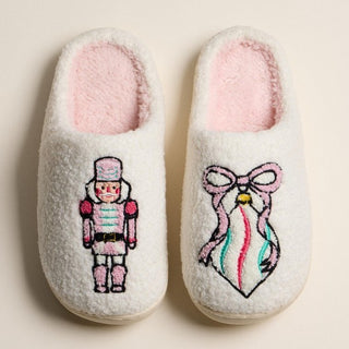 Fuzzy slippers in pink with a nutcracker and ribbon ornament design.