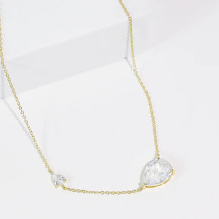 A delicate gold necklace with two crystal drops displayed on a white background.
