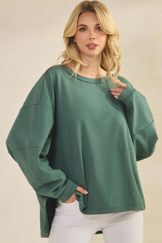 A sage green relaxed fit top with long sleeves and a crew neckline.