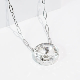 Silver necklace with an oval link chain and a large round crystal pendant.