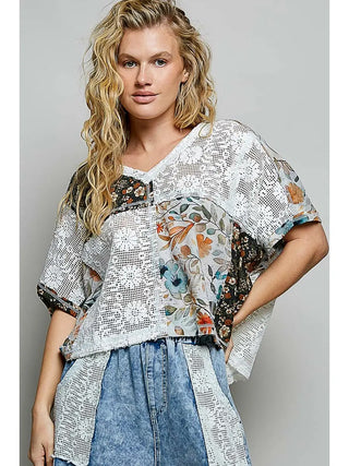 A woman wearing a V-neck lace sleeveless top in ivory multi with floral accents and a relaxed fit.