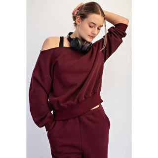 Woman wearing a dark cherry off-shoulder top made of French terry fleece.