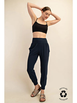 Person wearing navy joggers with side pockets, elastic waistband, and ribbed cuffs.