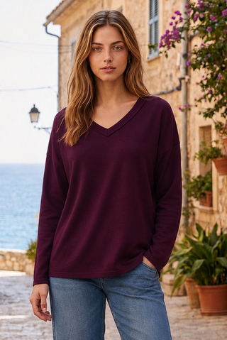 A woman wearing a cabernet V-neck top with long sleeves, standing outdoors.