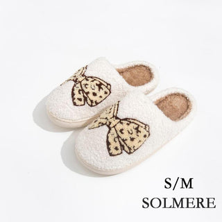 Plush slide-on slippers in white and tan with a leopard print bow accent.