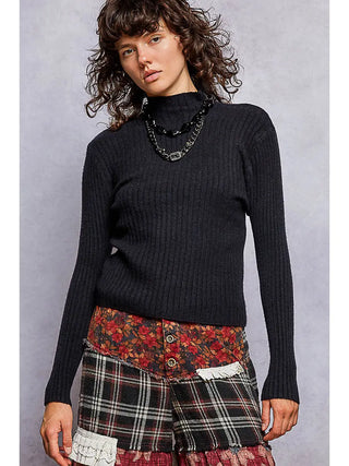 A black fitted rib knit sweater with a mock neck and long sleeves, worn by a model.