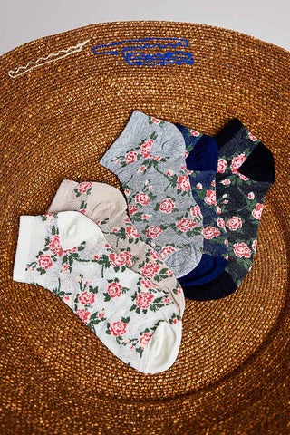 A collection of multicolor floral crew socks displayed on a woven surface.