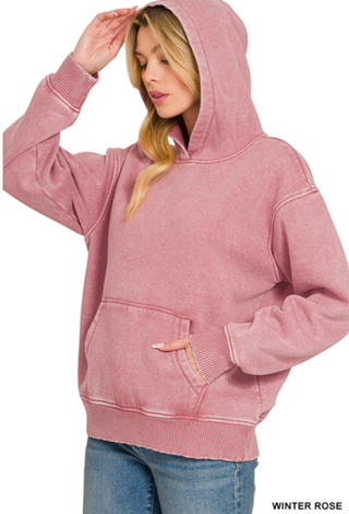 A woman wearing a Zenana Fleece Acid Wash Hoodie in Winter Rose with a kangaroo pocket.