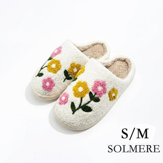 White slide-on slippers with pink and yellow floral embroidery.