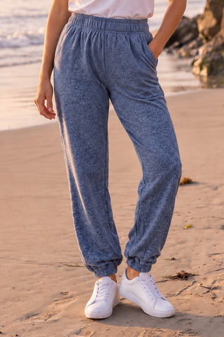 Woman wearing true navy pants with a textured design, elastic waistband, and relaxed fit, standing on a beach.