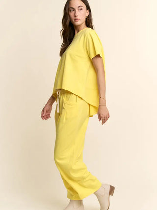 A woman wearing a yellow pleated top and pants set from Davi & Dani.