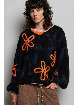 Round neck sweater in black with pink and orange floral embroidery, worn by a model with long sleeves.