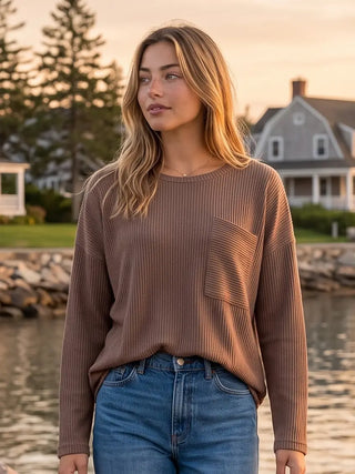 A woman wearing a mocha ribbed crew neck top with long sleeves, standing outdoors.