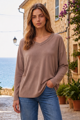 A woman wearing a mocha V-neck top with long sleeves, standing outdoors.