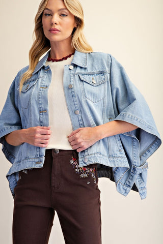 A woman wearing a washed denim jacket with dolman sleeves and front button closure.