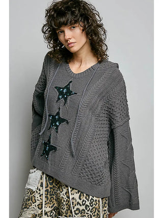 A woman wearing a charcoal hoodie with a V-neck and star lace patches, featuring a 3D weave design.