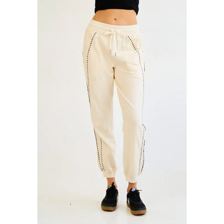Ecru jogger pants with piping details and a drawstring waist, shown on a model.