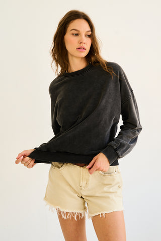 A woman wearing a black burnout washed sweatshirt with a relaxed fit.