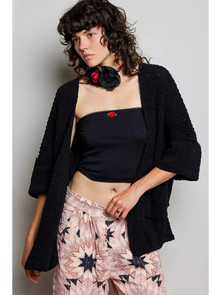 A model wearing a black chenille sweater cardigan with long sleeves and pockets.