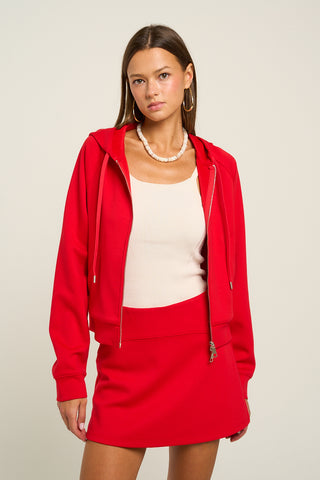 Red zip-up hoodie with drawstring hood, worn by a model.