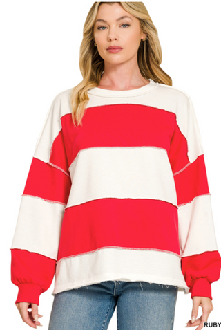 A woman wearing a Zenana French Terry color block top in ruby with exposed seams.