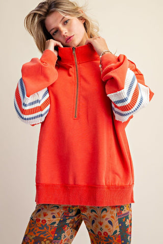 A model wearing a hot coral washed terry half zip pullover with striped sleeves.